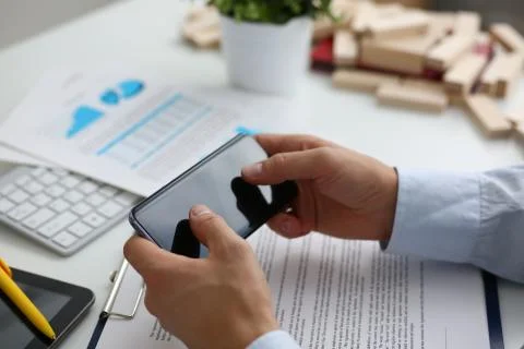 Businessman studying documents with help of smart phone Stock Photos