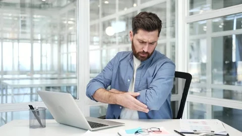 Businessman suffering from elbow pain while sitting at desk at workplace Stock Footage 315031648