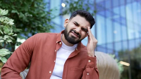 Businessman is suffering from headache while sitting on bench near modern office Stock Footage 304595910