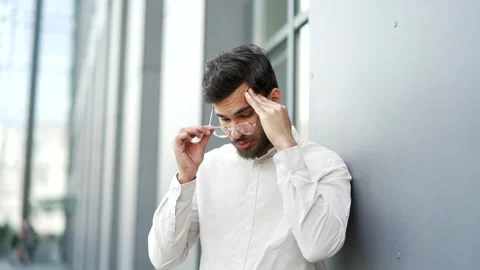 Businessman is suffering from headache while standing near modern office buildin Stock Footage 311371831