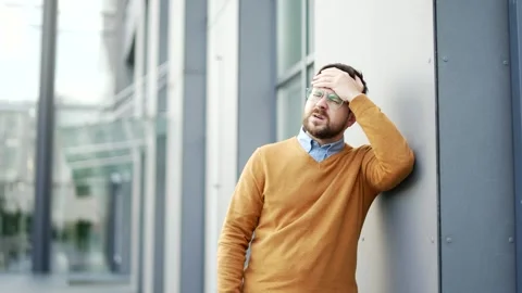 Businessman suffering from headache while standing on street near modern office  Stock Footage 330240714