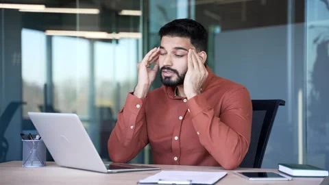 Businessman suffering from headache while working on laptop sitting at workplace Stock Footage 305646541