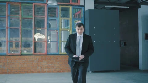 Businessman in a suit and with documents in hand walking in the office, talking Stock Footage 107398505