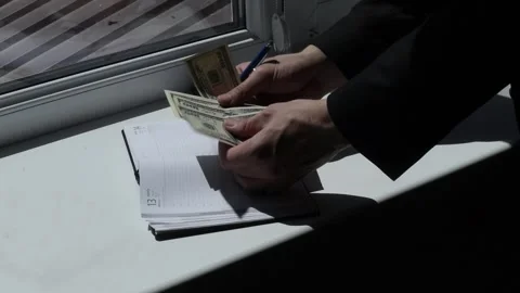 Businessman in a Suit Counting Dollars and Writing in a Notebook Indoors Video stock 240211953
