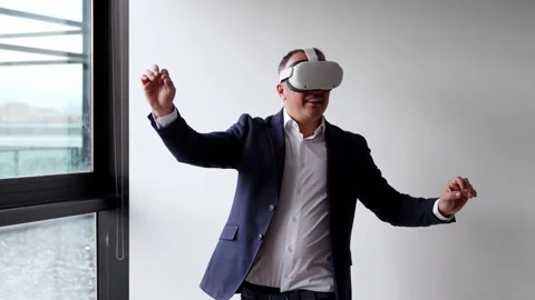 A businessman in a suit interacts with a VR headset, engaging with virtual re Stock Footage 275861086