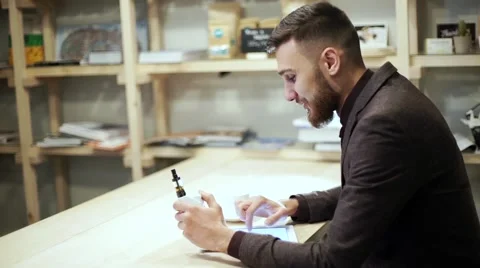 Businessman in a suit reading on tablet with an e-cigarette vape Stock Footage 56891827