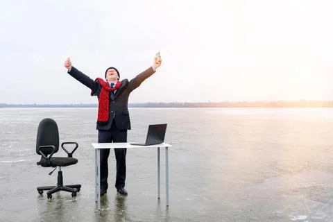Businessman in suit stands with outstretched hands at a table in the middle lake Stock Photos