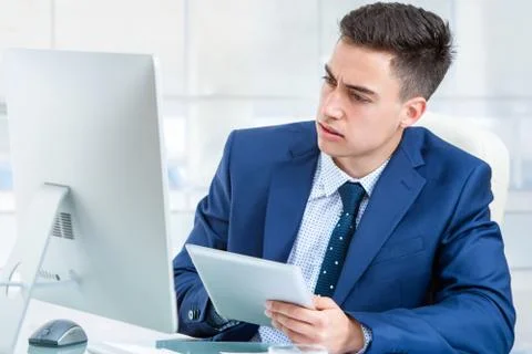 Businessman synchronizing digital tablet with computer. Stock Photos