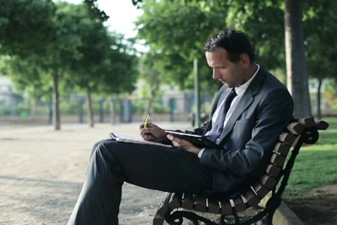 Businessman with tablet computer and documents in the park, dolly shot NTSC Stock Footage 11150145