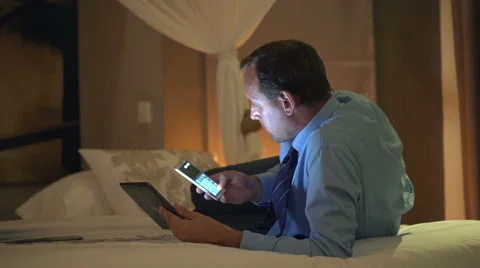 Businessman with tablet computer calculating data on smartphone lying on bed  HD Stock Footage 45443546
