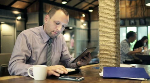 Businessman with tablet computer calculating data on smartphone in cafe HD Stock Footage 49699968