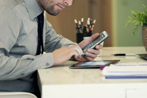 Businessman with tablet computer calculating data on smartphone by table NTSC Stock Footage 49721806