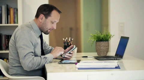 Businessman with tablet computer calculating data on smartphone by table HD Stock Footage 49721944