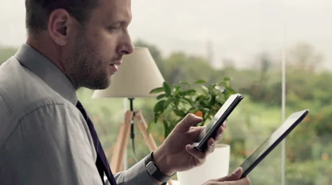 Businessman with tablet computer calculating data on smartphone in office Stock Footage 53141971