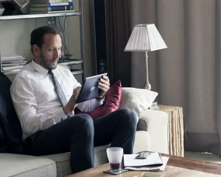 Businessman with tablet computer sitting on sofa at home PAL Stock Footage 57535508