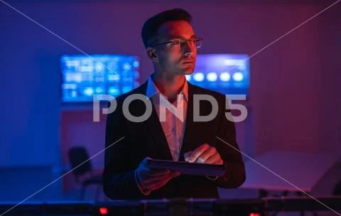 The businessman with a tablet working in a room with screens Stock Photos
