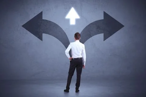 Businessman taking a decision while looking at arrows on the wall concept Stock Photos