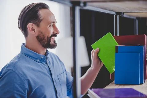 Businessman taking notebook from shelf Stock Photos