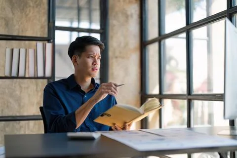 Businessman taking notes in the notebook, working over the computer, sitting at Stock Photos