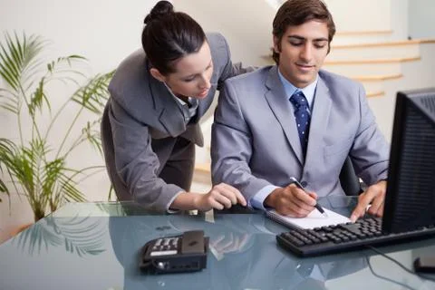 Businessman taking notes while getting mentored by colleague Stock Photos