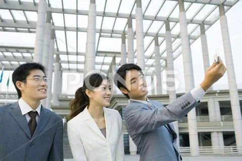 Businessman Taking Photo Of Self And Two Colleagues With Cell Phone