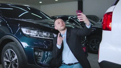 Businessman taking a selfie while standing near a luxury car in a modern Stock Footage 304713740