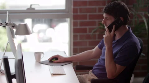 Businessman talking on mobile and using computer at office. Stock Footage 64104351