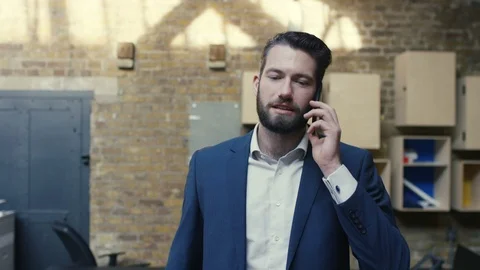 Businessman talking on mobile phone while walking in office Stock Footage 107889959