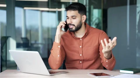 Businessman talking on mobile phone while sitting at work desk at workplace  Stock Footage 305655362