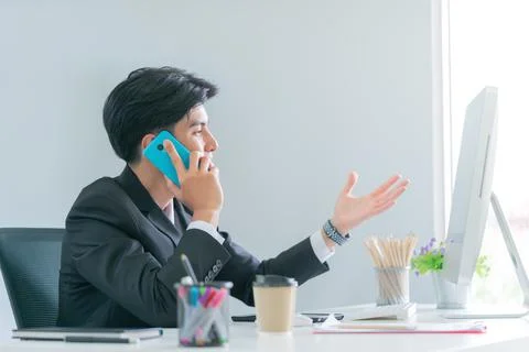 Businessman is talking on the mobile while looking at blank computer screen i Stock Photos