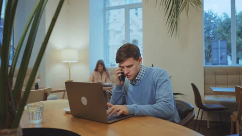 Businessman talking on phone and using laptop in cafe Stock Footage 164095343