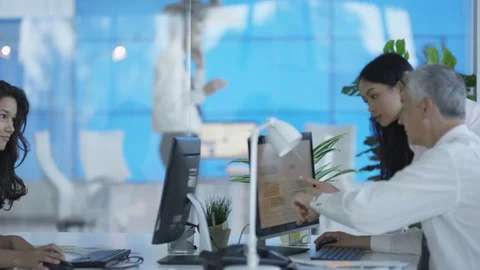 Businessman talking on phone while colleagues work on computer in office Video stock 108130441