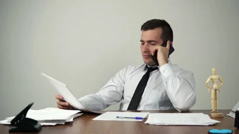 Businessman talking on the phone while sitting at his desk in the office Stock Footage 158817622