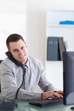 Businessman talking on the phone while using his computer 스톡 사진