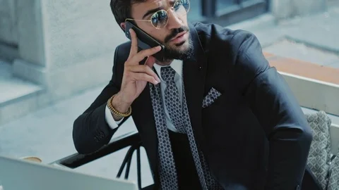 Businessman talking seriously on the phone while working on laptop 스톡 동영상 96298926