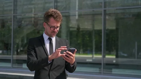 Businessman is talking by videocall and using smartphone on street Stock Footage 143908527