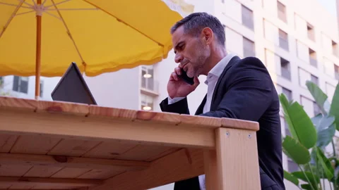 Businessman talks on a smartphone while working with laptop outdoors. Stock Footage 267831904