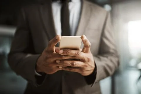 Businessman texting on a phone to send a formal business sms text inside an Stock Photos