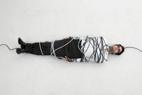 Businessman tied up with computer cable, elevated view Stock Photos