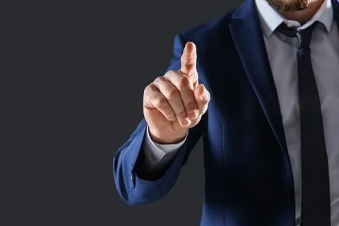 Businessman touching empty virtual screen against dark background, focus on h Fotos de archivo