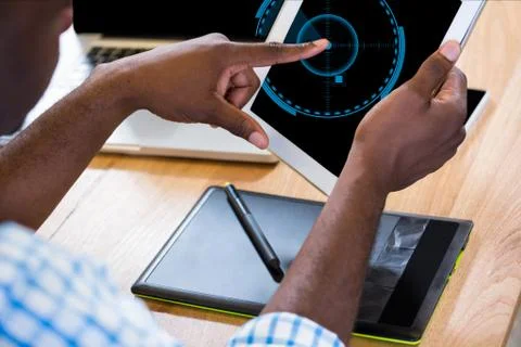 Businessman is touching his tablet computer screen against desk background Stock Photos