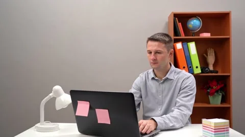 Businessman typing on a computer laptop, sitting at a desk, very focused. Office Stock Footage 149296440