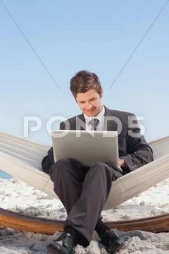 Businessman typing on his laptop in a hammock and smiling Stock Photos