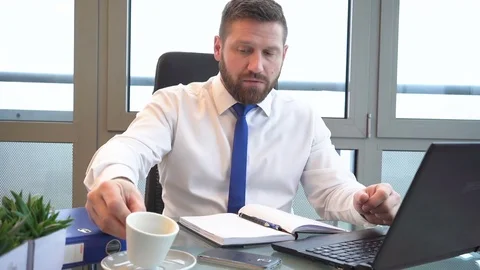 Businessman typing on laptop computer, drinks coffee in office, portrait Stock Footage 72499930