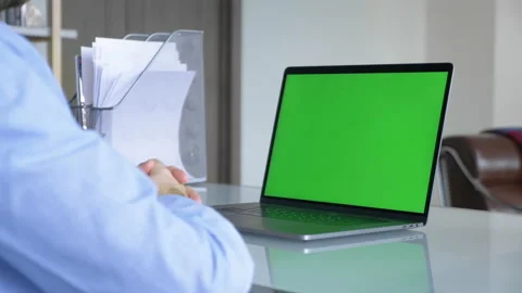 Businessman typing on laptop keyboard with a green screen on laptop display Stock Footage