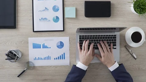 Businessman typing monthly report on laptop in the office, top view of workplace Stock Footage