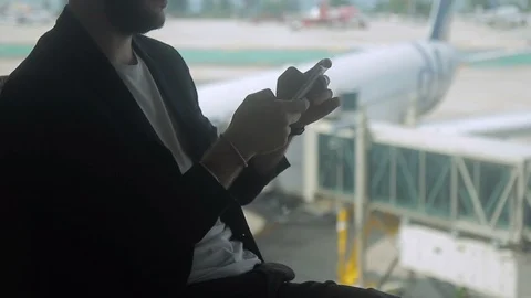 Businessman is typing text on the screen of his smartphone in the airport. Stock Footage 85618554