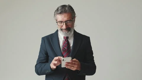 Businessman typing text on smartphone, isolated on gray background Stock Footage 255963339