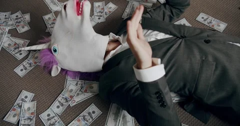 Businessman with unicorn mask counting stack cash money dollar profit salary Stock Footage 260481245