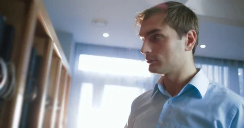 Businessman uses a tablet computer standing next to a large shelf Stock Footage 82969922